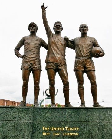 Statuen «The United Trinity» står utenfor East Stand i Sir Matt Busby Way vis-a-vis statuen av den berømte manageren. Fra venstre George Best (1945-2005), Dennis Law (1940 - ) og Sir Bobby Charlton (1937 -). Statuen ble reist til 40 års jubileet for  klubbens første seier i Europacupen i 1968.